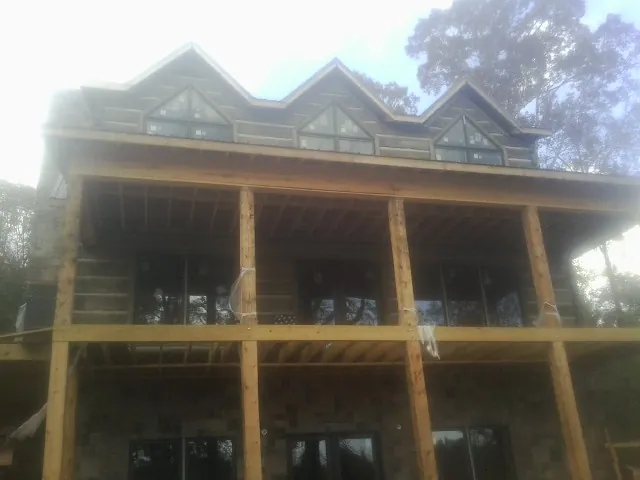 Dormers and porch framing on a large log home under construction — Roof Coating work by our crew in Saint Charles